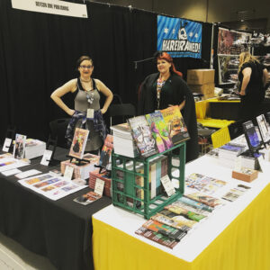 Two women standing at a table selling books.